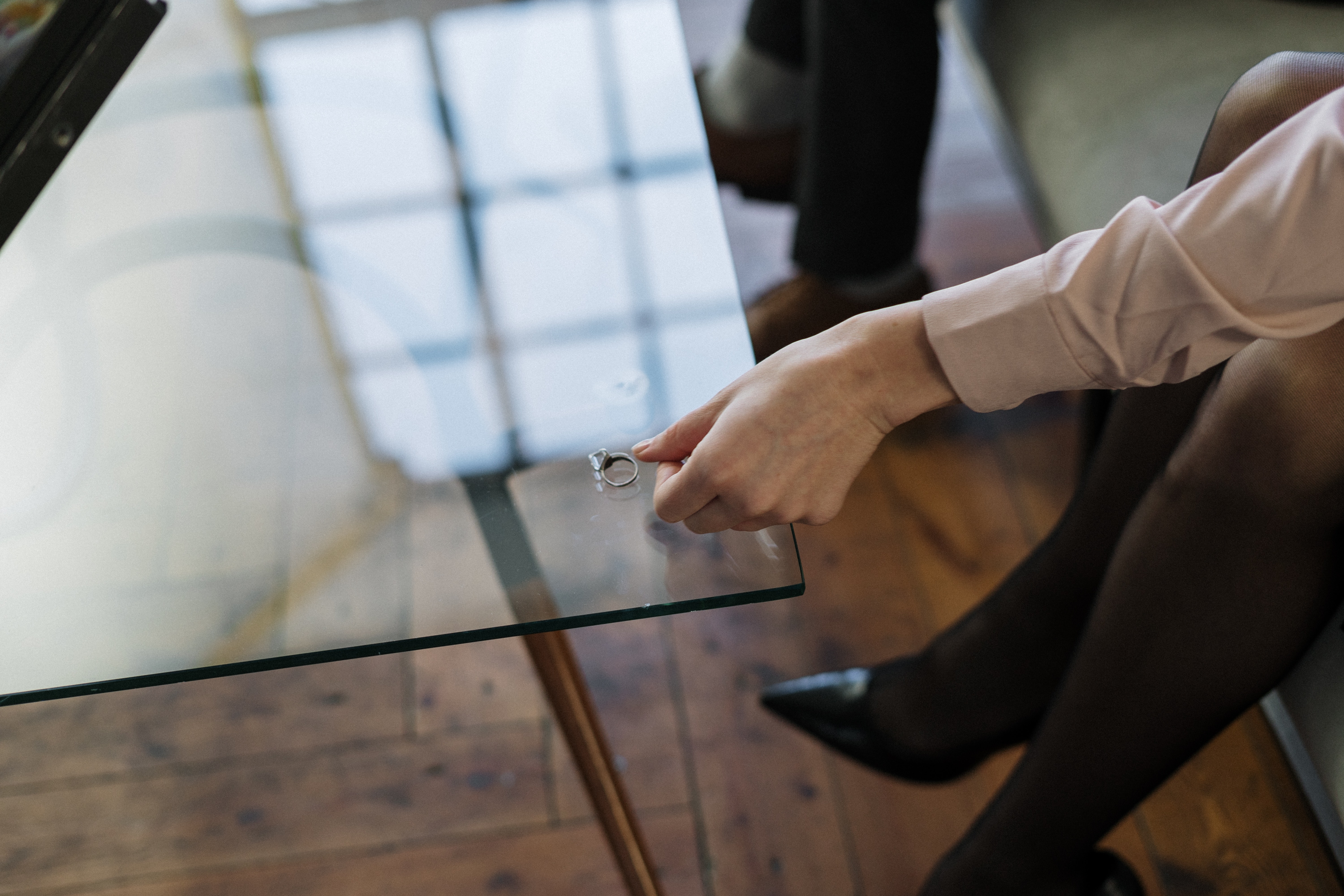 woman removing wedding ring and placing on glass table